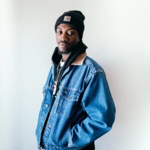 man in blue denim jacket wearing black cap